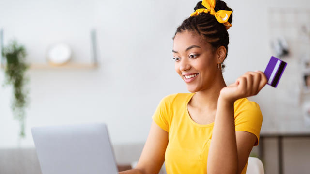 Black woman using computer and credit card at home 