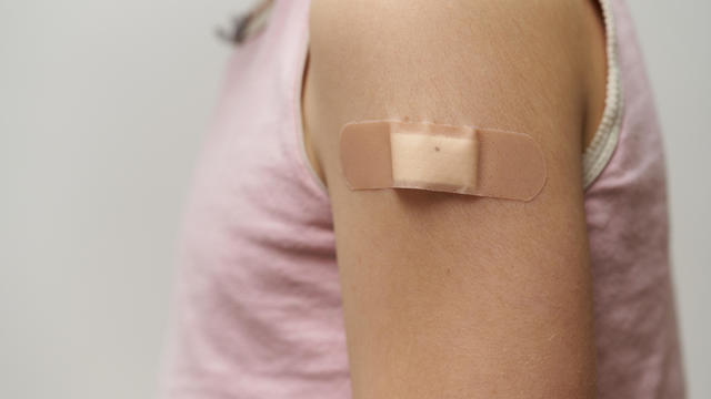 Close up of band aid, on the arm of a caucasian girl after giving her the vaccine 