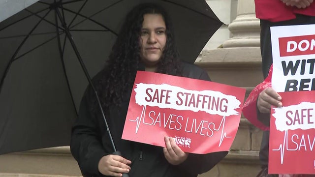 A nurse holds a sign that says "Safe staffing saves lives." 