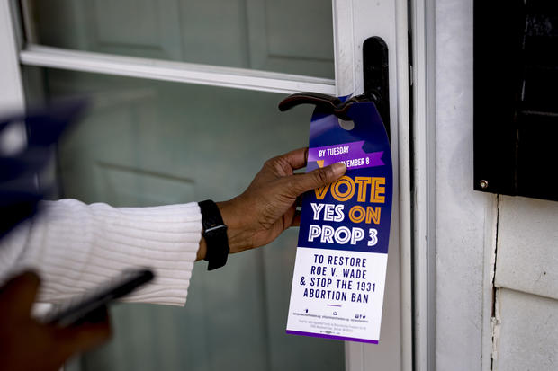 Darci McConnell places a door tag in support of Proposal 3 on a door in Plymouth, Michigan, on Oct. 30, 2022. 