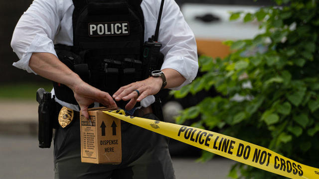 A police officer pulls police tape after a shooting in a 