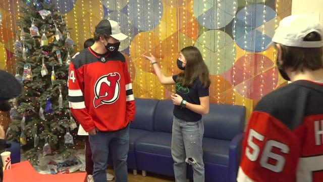 Pediatric cancer survivor Grace Eline shows New Jersey Devils player Jack Hughes and another player the Giving Tree in the Beth Israel Medical Center. 