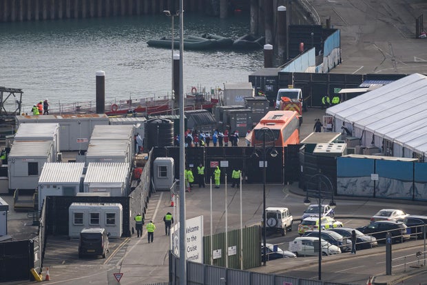 A line of migrants can be seen boarding a bus after being rescued in the English Channel, December 14, 2022, at the port in Dover, England