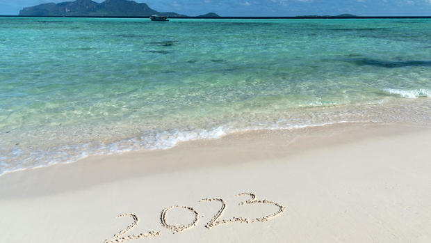 Happy New Year 2023 written on sand beach 
