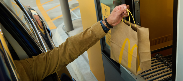 Hand holding McDonald's bag above conveyor belt