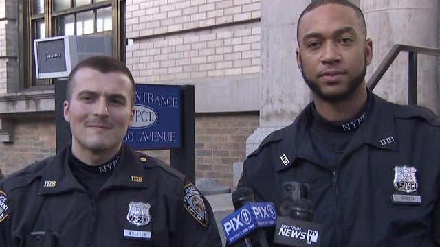 Two NYPD officers speak to reporters. 