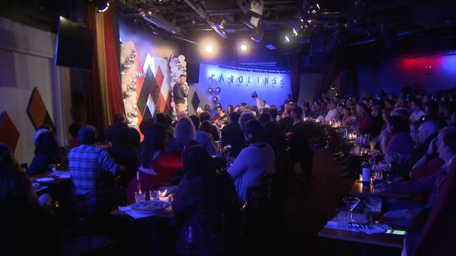 A performer stands on stage while a packed room watches at Carolines on Broadway. 