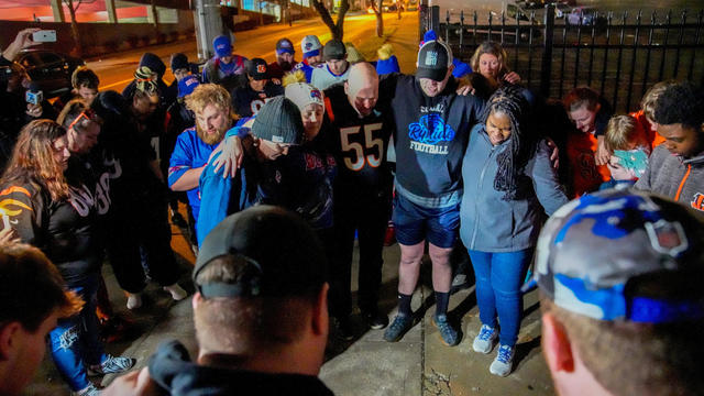 Football fans pray outside the University of Cincinnati Medical Center after Buffalo Bills defensive back Damar Hamlin collapsed 