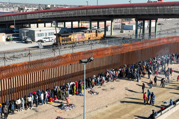 As seen from an aerial view, migrants line up along the U.S.-Mexico border fence to apply for asylum in the United States on Dec. 21, 2022, as viewed from Ciudad Juárez, Mexico. 