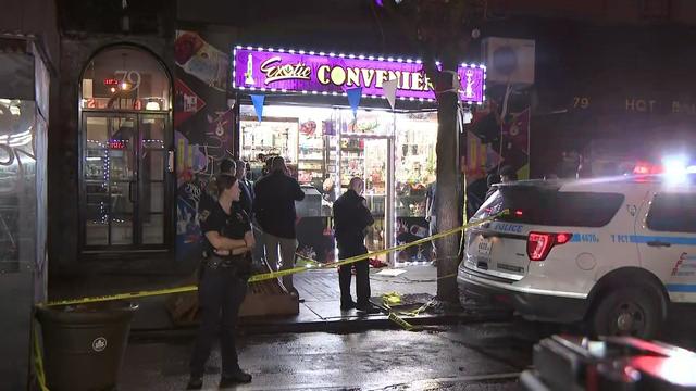 Police stand outside a smoke shop blocked off by crime scene tape. 