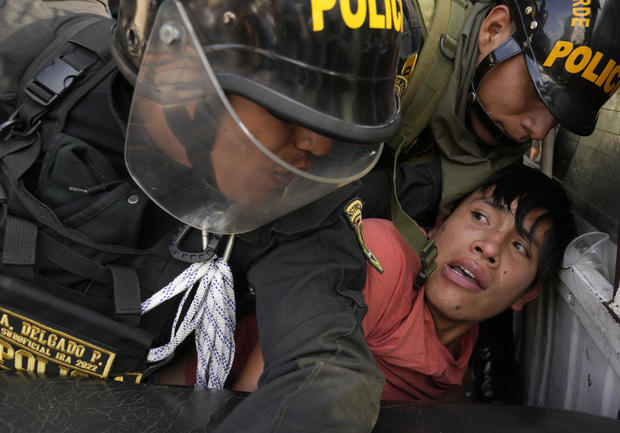An anti-government protester who traveled to the capital from across the country to march against Peruvian President Dina Boluarte, is detained and thrown on the back of police vehicle during clashes in Lima, Peru, Thursday, Jan. 19, 2023
