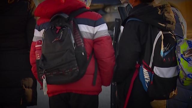 A group of students stand together wearing backpacks. 