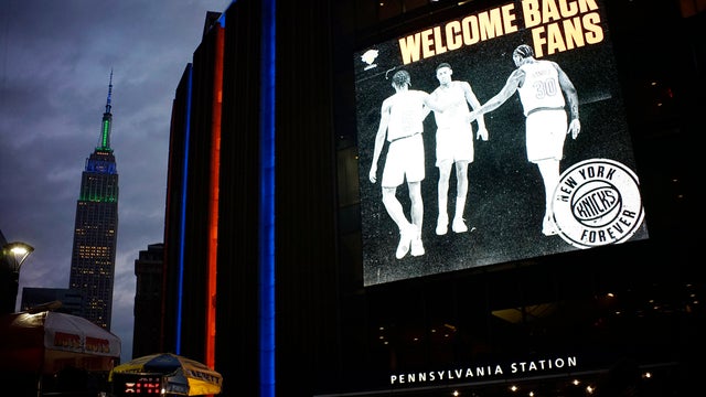 Night view of exterior of Madison Square Garden with Empire State Building in background 