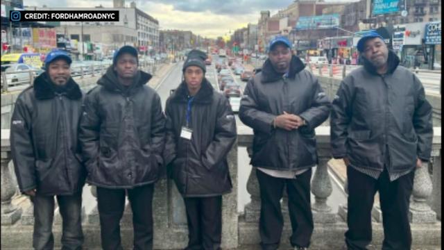 Five security officers stand along Fordham Road. 