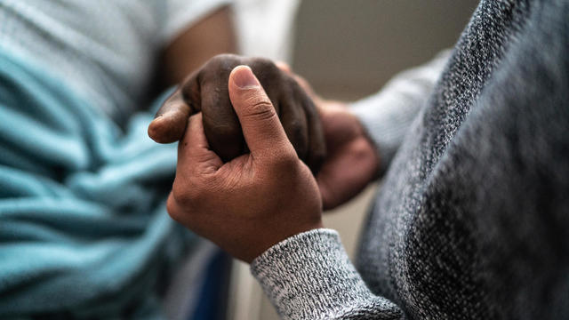 Son holding father's hand at the hospital 