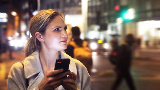 Lady in the city at night with her phone 