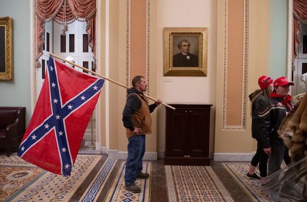Kevin Seefried holds a Confederate flag outside the Senate chamber on Jan. 6, 2021. 