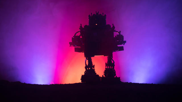 Silhouette of Giant robot. Futuristic tank in action with foggy fire sky background 
