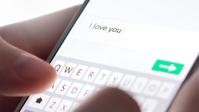 Sending I love you text message with mobile phone. Online dating, texting or catfishing concept. Romance fraud, scam or deceit with smartphone. Man writing comment. 