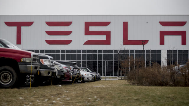 Cars parked outside Tesla facility on gray day 