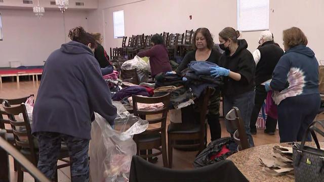 Volunteers sort and pack up piles of clothes. 