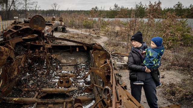A family in Ukraine examines the remains of a Russian tank destroyed in the war 
