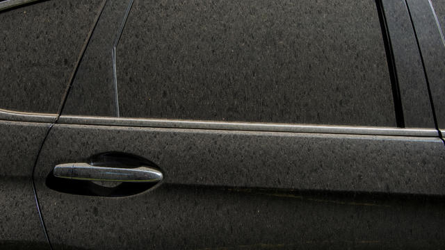 Detail of a dusty car parked in a city street 