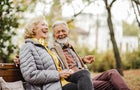Happy senior couple sitting on the bench in park 