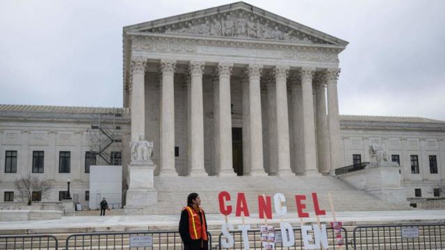 An activist stands next to a sign as they protest in front of the Supreme Court during a rally for student debt cancellation on Feb. 28, 2023. 