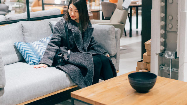 Young woman at furniture store choosing sofa 