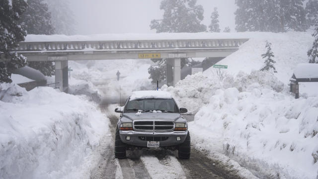 A truck drives through huge piles of snow in California 
