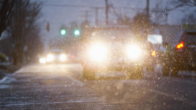 Car driving on snowy urban street at night 