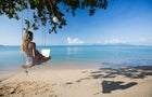 Thailand, woman using laptop on beach 