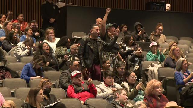People in the audience of a Perth Amboy school board meeting yelling. 