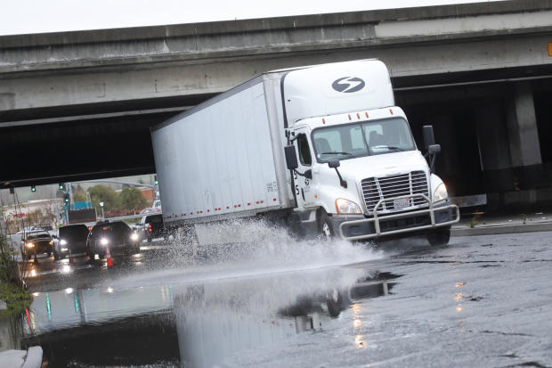 A truck drives through a flooded road after an atmospheric river storm system in Hayward, California, March 10, 2023. 