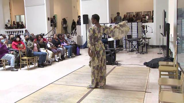 A model in a fashion show stands in front of an audience. 