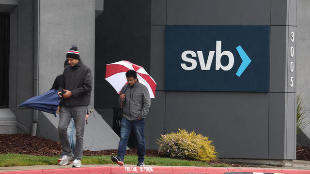 Two people walking in front of sign reading "SVB" 
