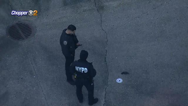 Two NYPD officers look at a gun on the ground. 