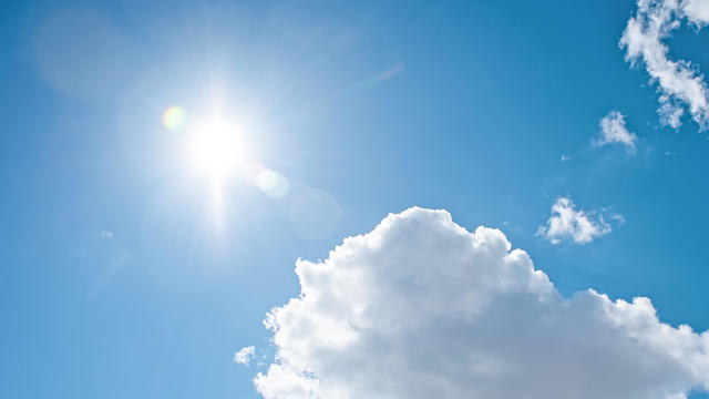 Clear blue sky background with clouds and bright sun 