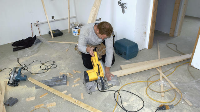 Builders cutting timber with circular saw 