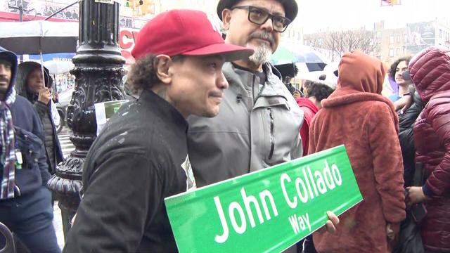 John Collado's nephew holds a street sign reading "John Collado Way." 