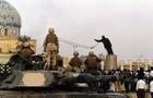 U.S. Marines and Iraqis watch as the statue of Iraqi dictator Saddam Hussein is toppled at al-Fardous square in Baghdad on April 9, 2003. 
