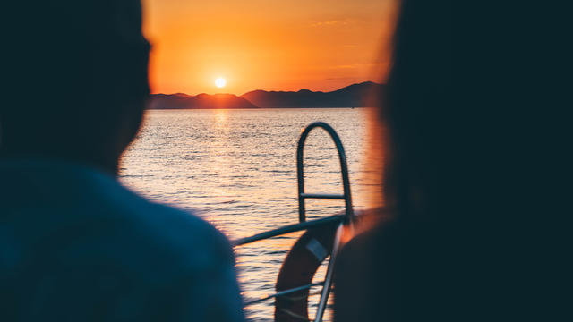 Couple relaxing on boat and looking at the sea sunset. 