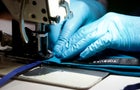 Close up of hands in blue gloves at sewing machine 