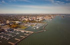 Incredible aerial city skyline panorama photograph of Sandusky, Ohio from the shoreline of the bay in Lake Erie with parks and harbors seen below on a sunny day. 