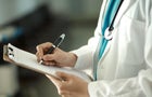 Doctor writing on clipboard 