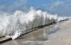 Large wave is crashing into beach wall 