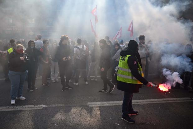 A protester holds a red flare during a demonstration after a court approved the key elements of French President Emmanuel Macron's unpopular pension reform plan, in Toulouse, southwestern France, on April 14, 2023. 