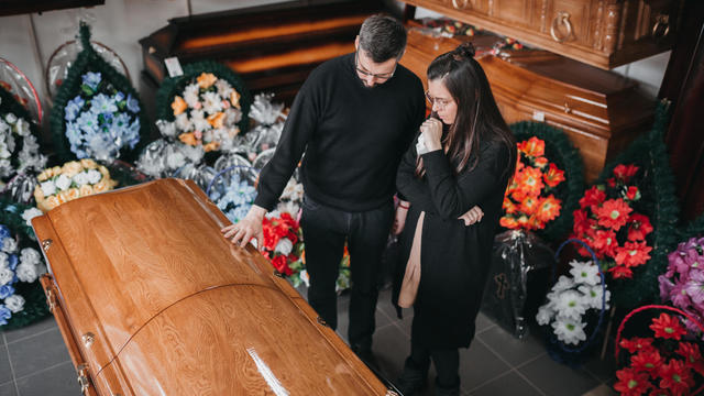 Undertaker showing coffins and crosses to a widow 