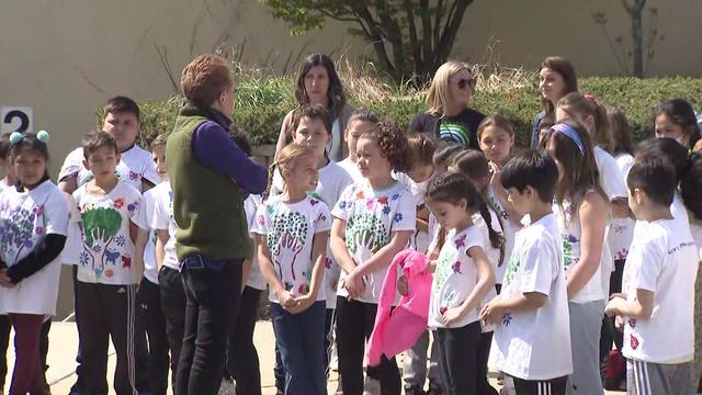 CBS2's John Elliott stands with elementary school students wearing custom Earth Day t-shirts. 